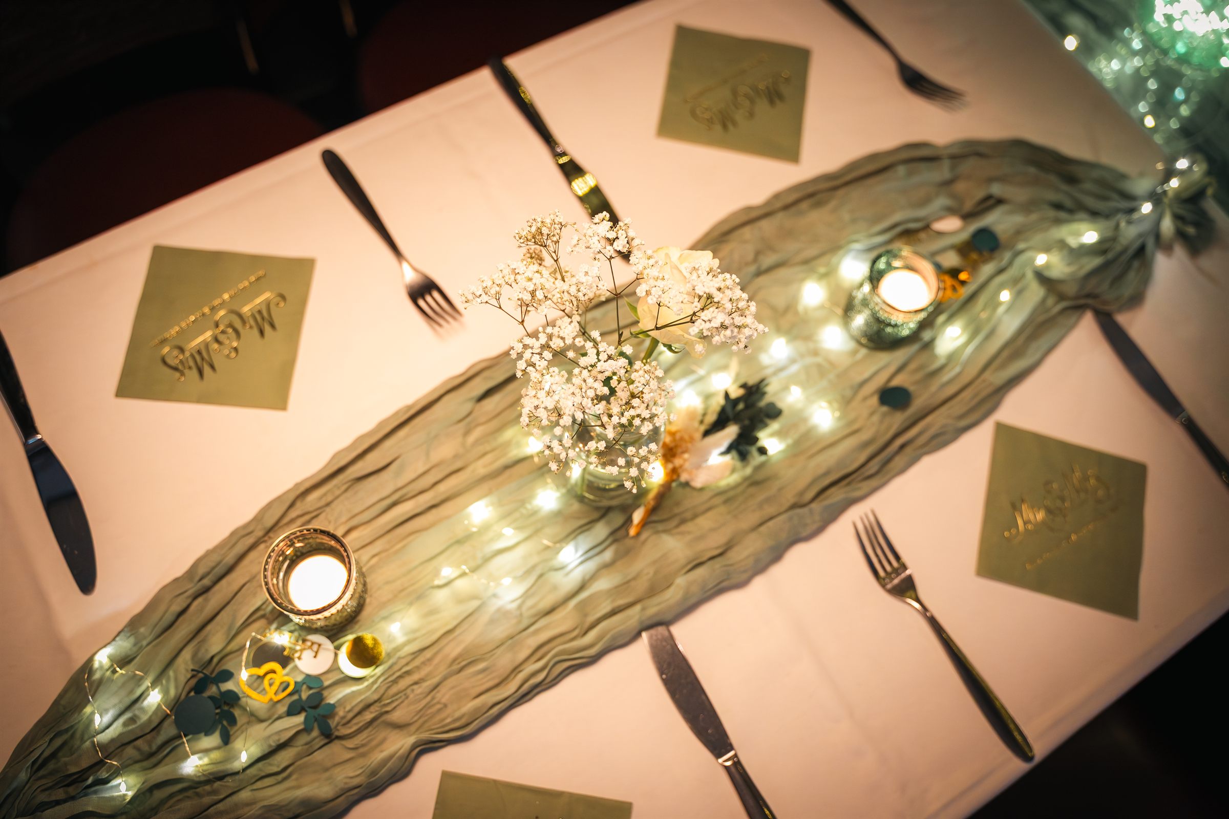 Festlich gedeckte Hochzeitstafel mit Tischläufer, Lichterkette, Kerzen und Schleierkraut