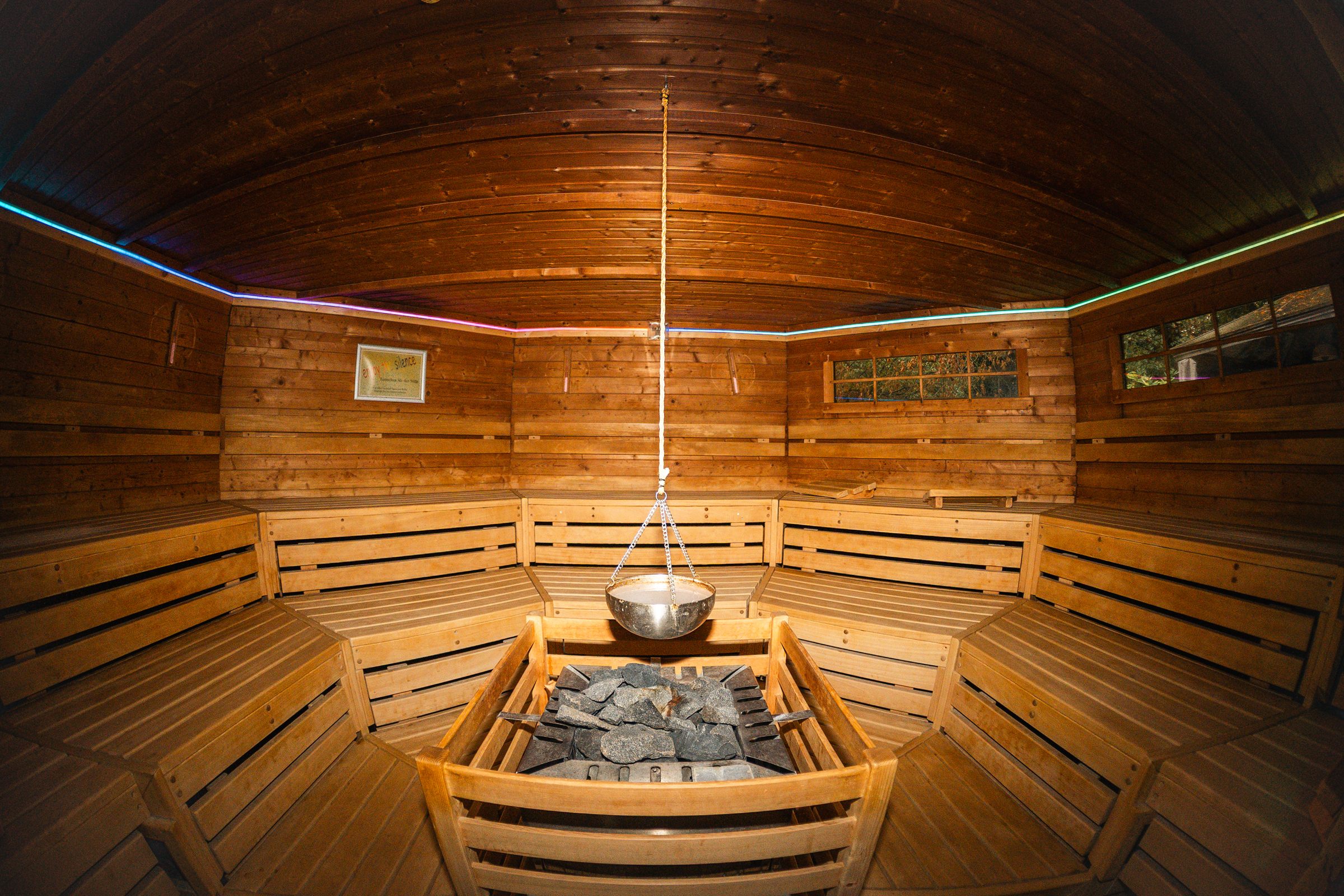 Biosauna mit Holzbänken rundum, in der Mitte der Saunaofen mit Steinen und darüber eine Schale